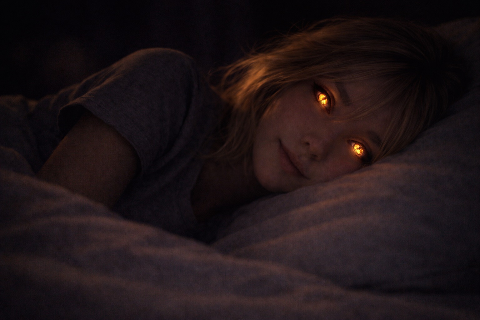 Kasha recostada en la cama, mirando de lado en la penumbra, con los ojos brillando suavemente en tonos dorados.